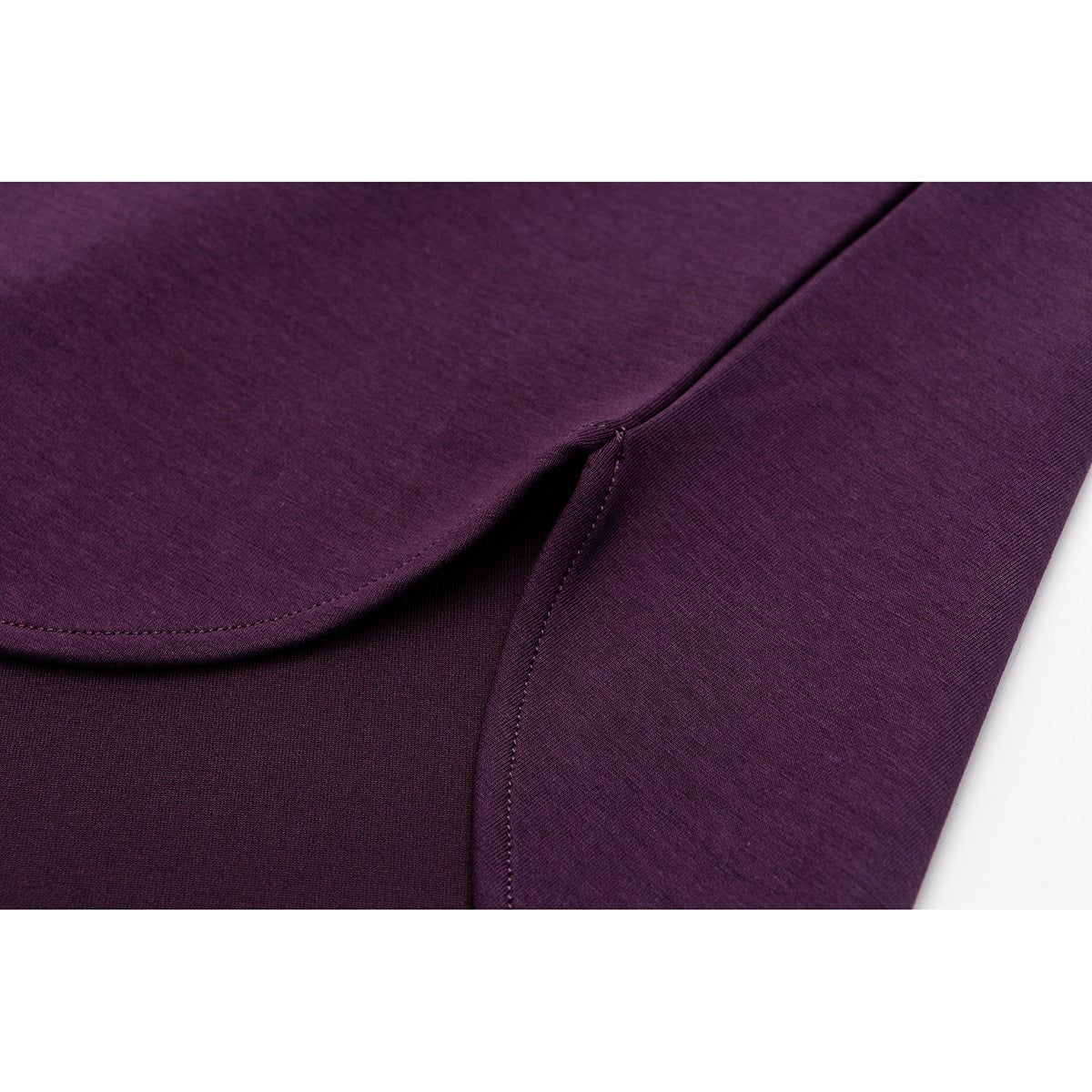 Close-up of plum T-shirt fabric showing a curved seam and an overlapping stitched section.