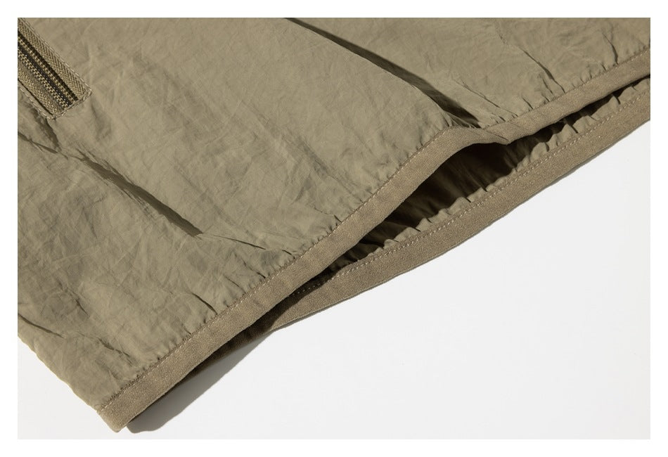 Close-up of the khaki garment hem with visible stitching and a glimpse of a zipper pocket.