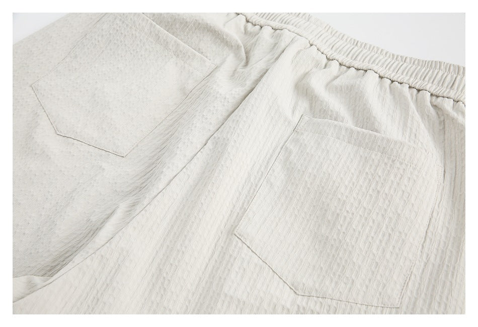 Close-up of the off-white shorts’ elastic waistband and two patch pockets.