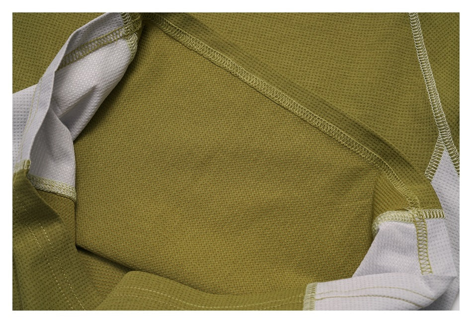 Close-up of olive green knit garment fabric and overlock seams, with white fabric panels visible at the edges.