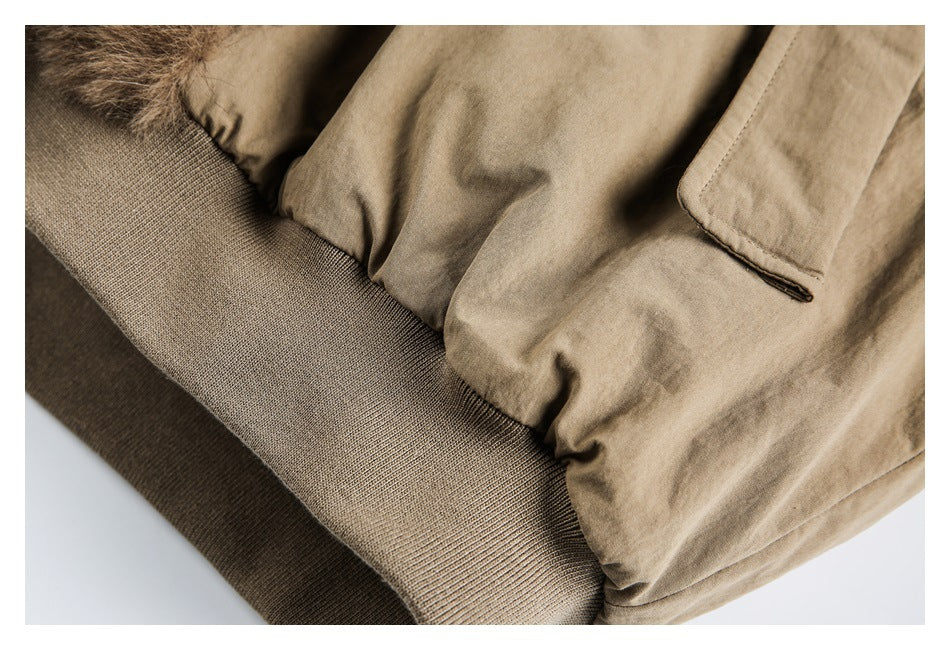 Close-up of a tan coat’s pocket and dark ribbed hem.