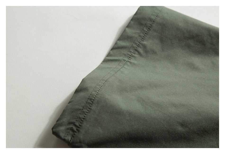 Close-up of a stitched edge on dark olive-green garment fabric.