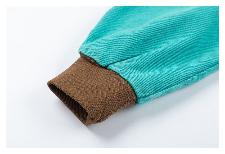 Close-up of a turquoise jacket sleeve ending in a brown ribbed cuff.