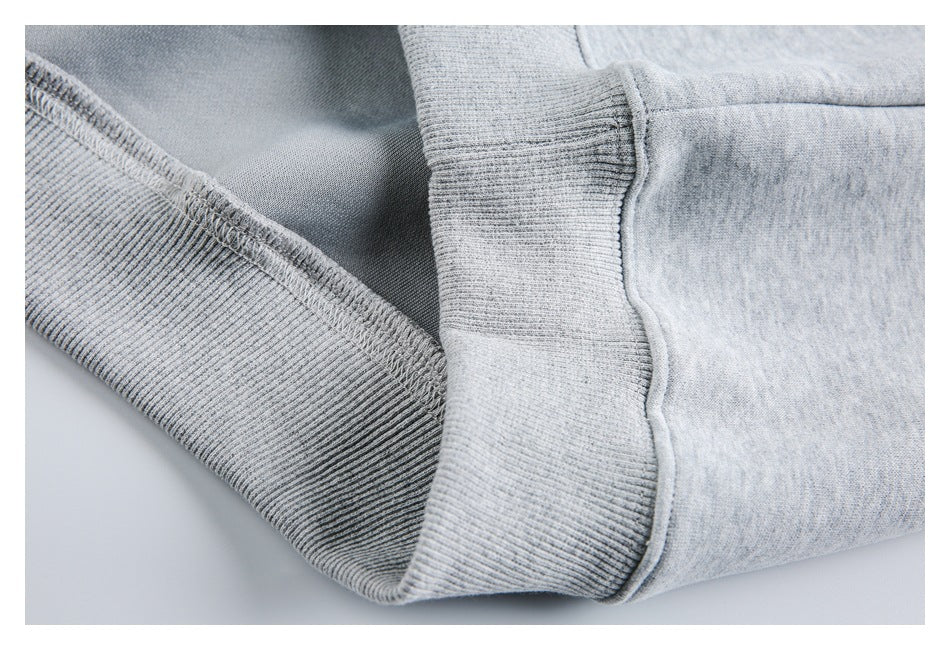 Close-up of a ribbed edge and stitched seam on a light gray heathered garment.