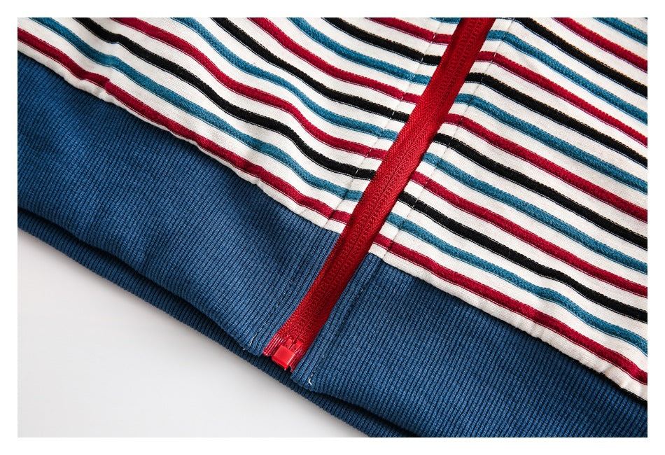 Close-up of a red zipper and blue ribbed trim on a white garment with red, teal, and black stripes.