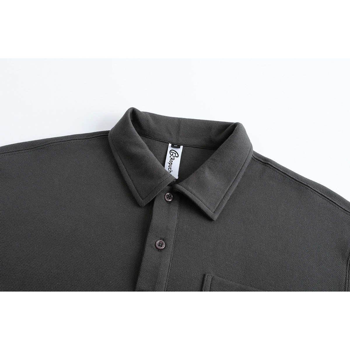 Upper front of a charcoal long-sleeve polo shirt with a pointed collar, button placket, and chest pocket.