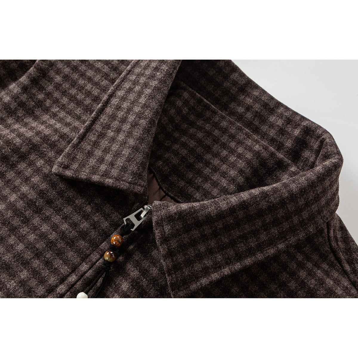 Close-up of a dark brown check jacket collar and zipper with a beaded pull.