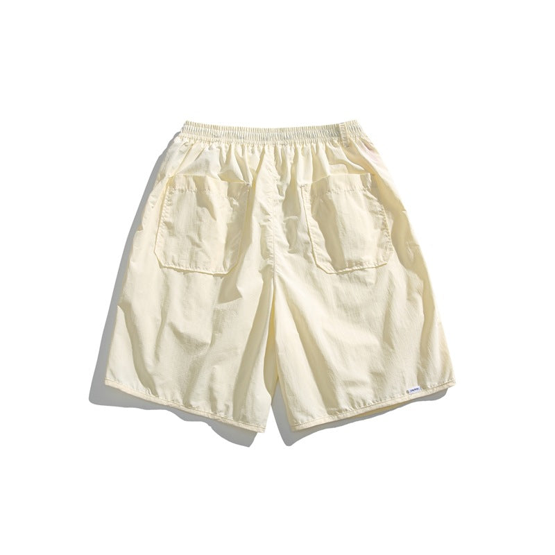 Back view of cream shorts with an elastic waistband and two large rear patch pockets, on a white background.