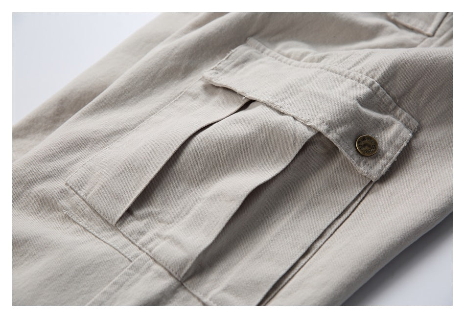 Close-up of a beige trouser cargo pocket with a flap and small metal button.
