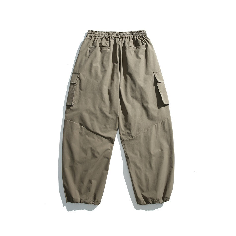 Back view of taupe cargo pants with an elastic waistband, rear pockets, flap side pockets, and gathered cuffs.