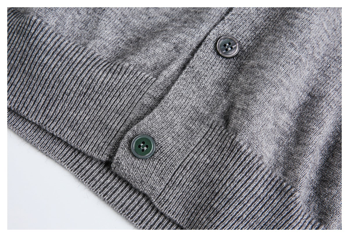 Close-up of a gray cardigan hem and placket with ribbed trim and two buttons.
