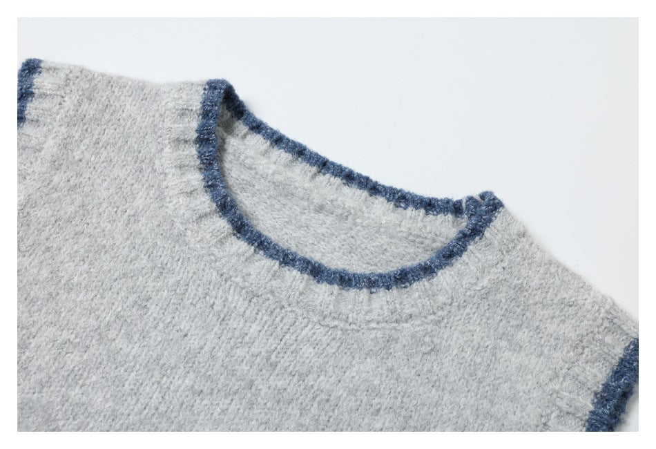 Close-up of a light gray knit top's round neckline and dark blue trim.