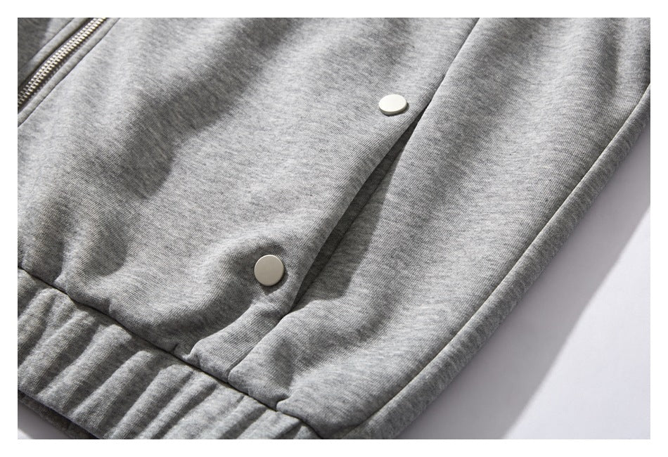 Close-up of the heather gray jacket's front snaps, zipper edge, and ribbed hem.