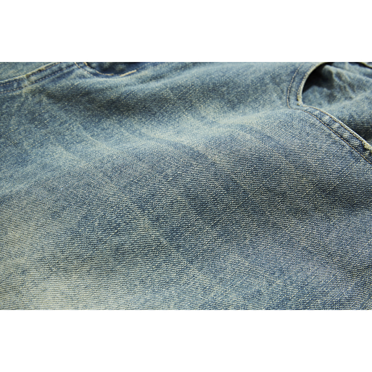 Close-up of faded blue denim with a curved seam and visible twill texture.