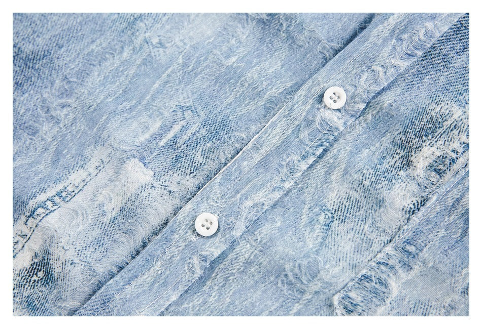 Close-up of the white buttons and frayed placket on a light blue distressed denim shirt.