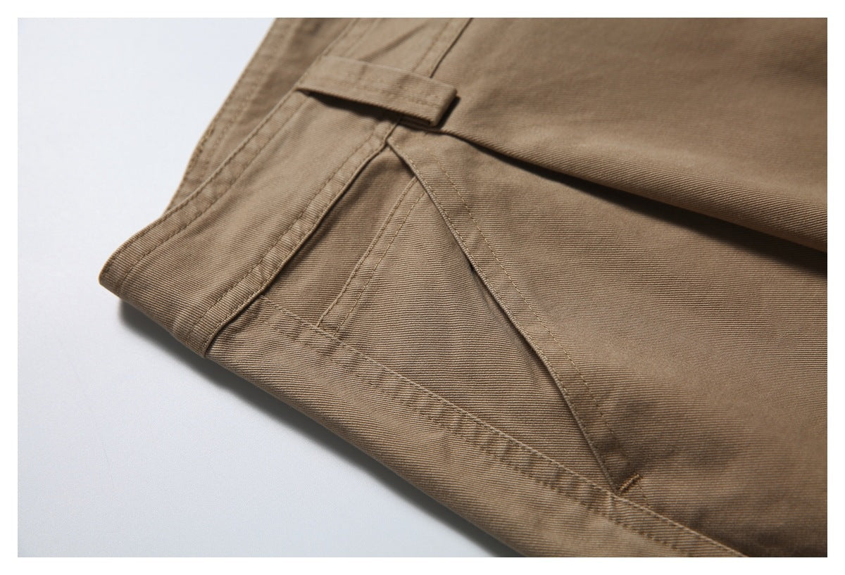 Close-up of tan trousers showing a stitched pocket edge and fabric tab.