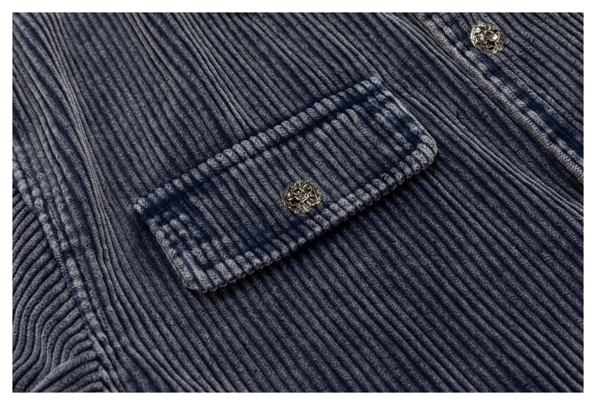 Close-up of a blue-gray ribbed corduroy garment with a flap pocket and ornate metal buttons.