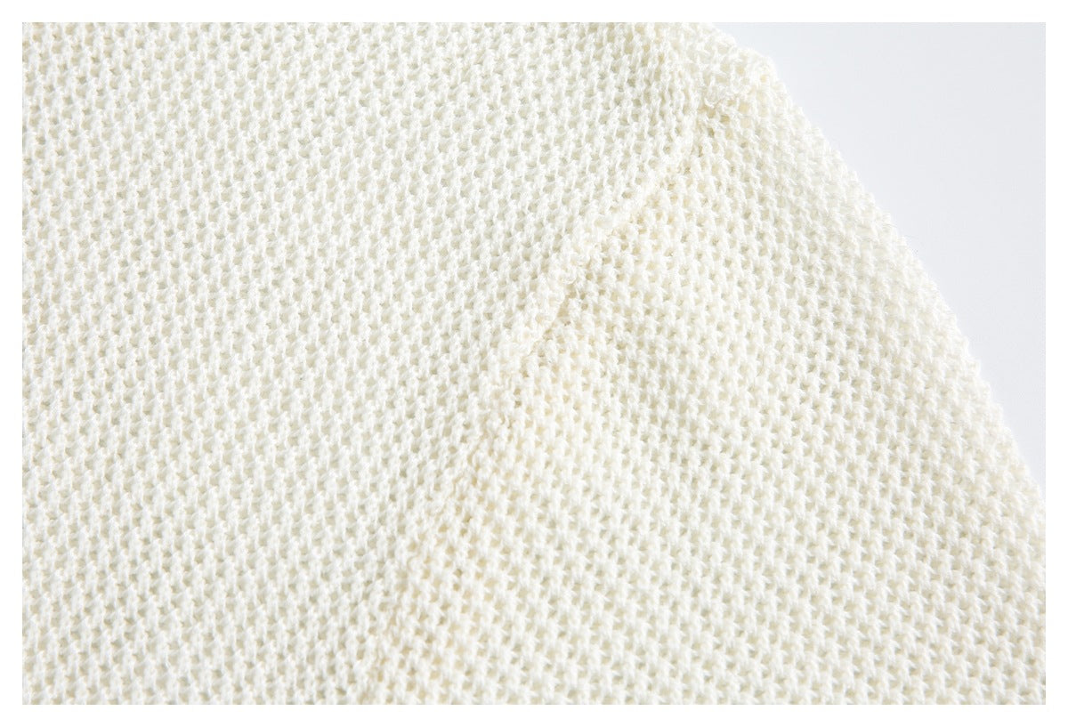 Extreme close-up showing the ivory sweater's open, textured knit stitch pattern.