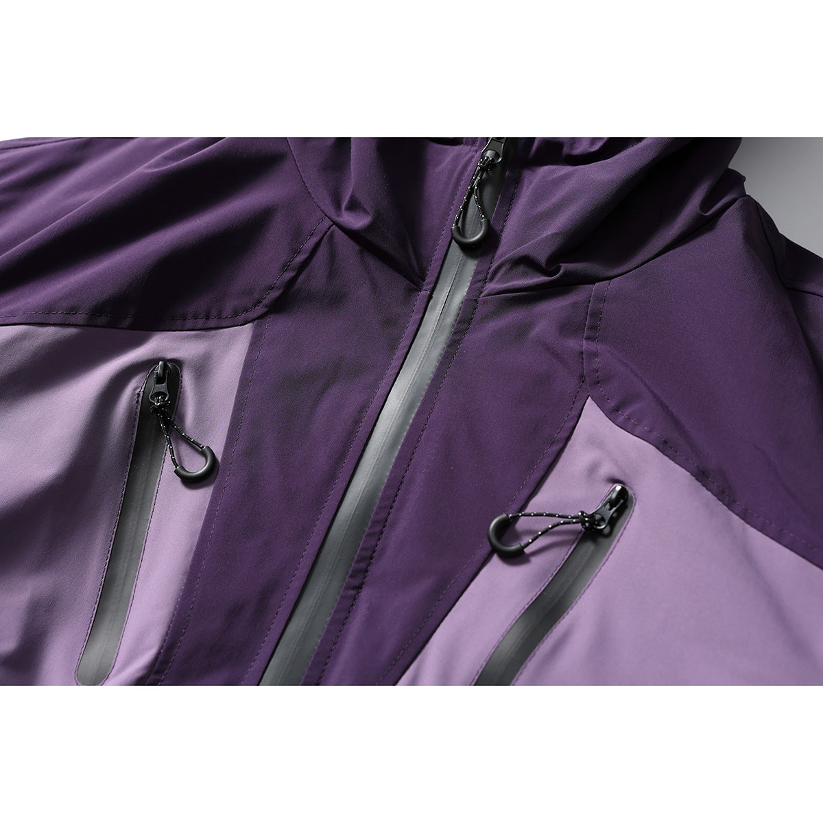 Close-up of a purple color-block jacket with a central zipper and two zippered chest pockets.