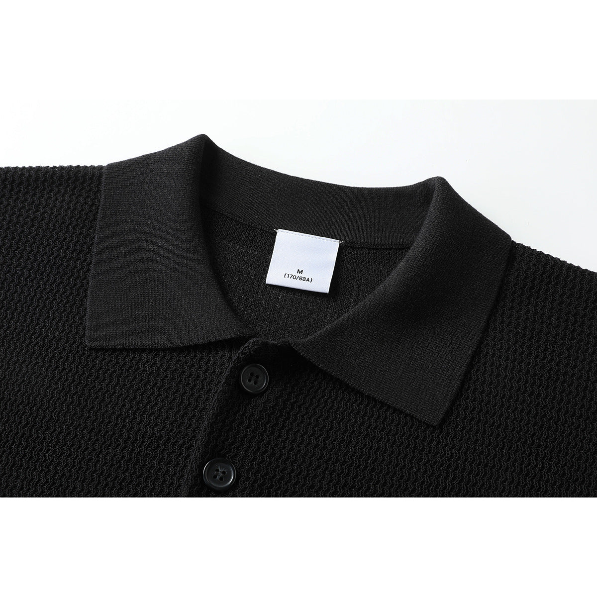Close-up of a black textured polo shirt collar, two buttons, and a small size label.