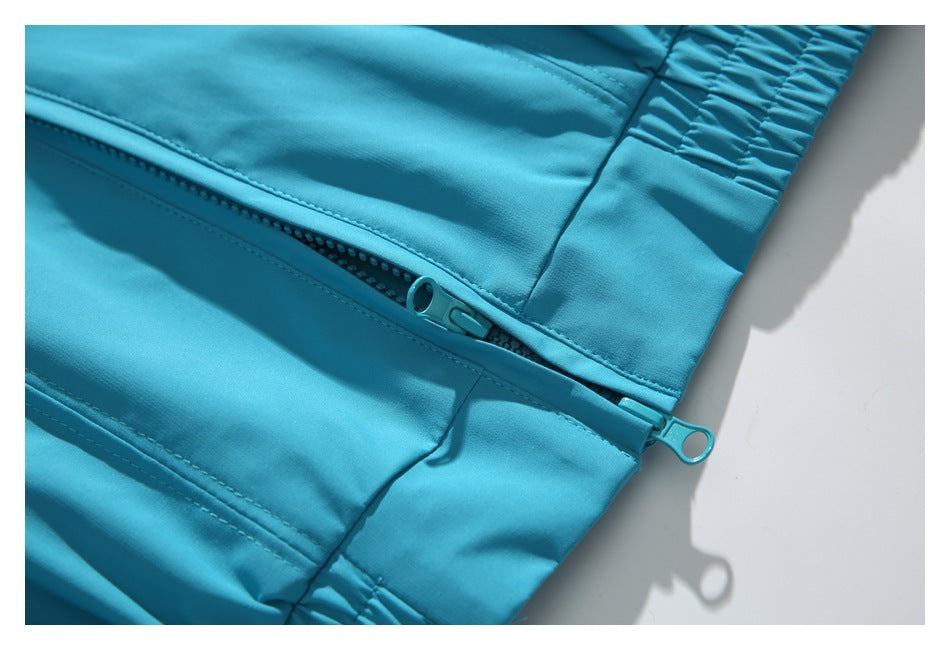 Close-up of the turquoise jacket's open zipper and gathered hem.