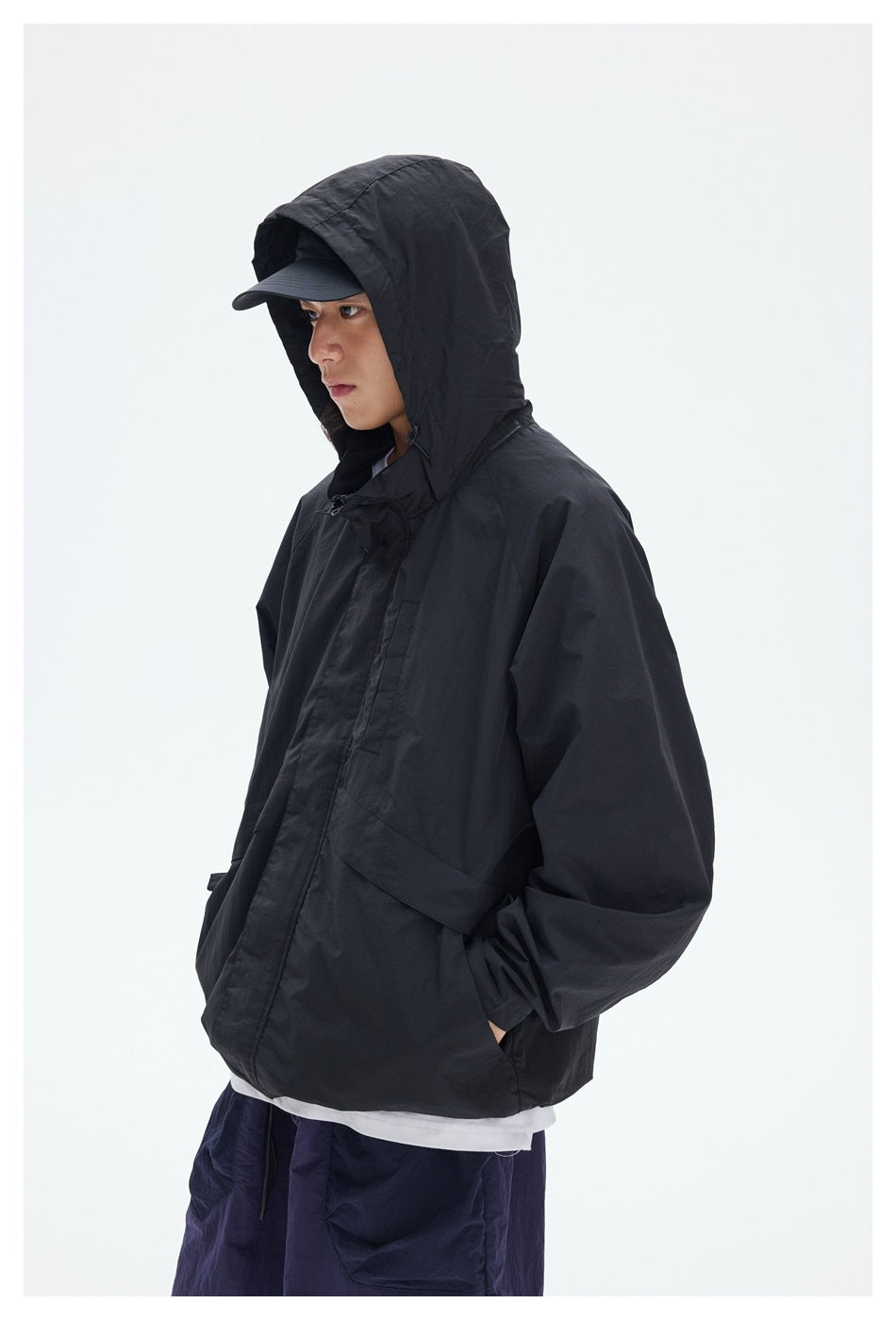 Closer view of a model wearing a black hooded jacket over a white shirt with purple shorts.