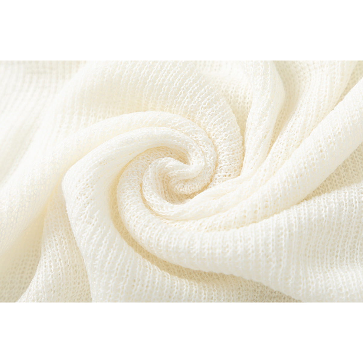 Close-up of ivory open-knit fabric gathered into soft folds.