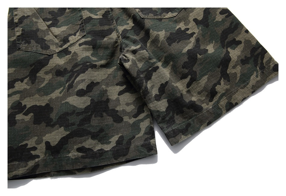 Close-up of a short sleeve and chest pocket on a green, brown, and black camouflage shirt.