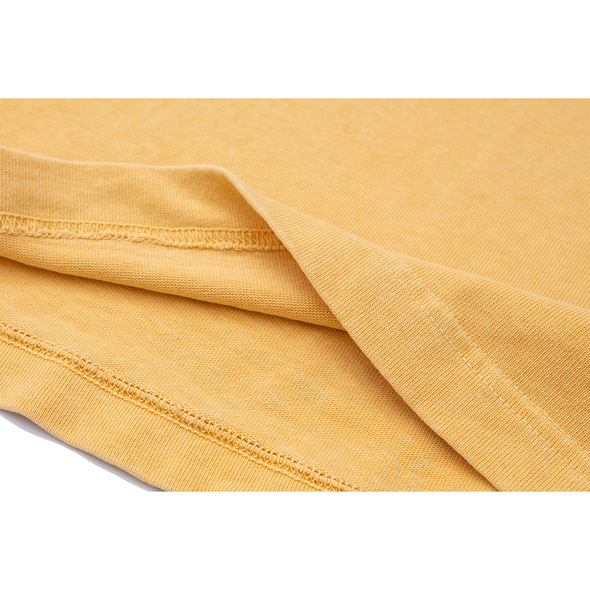 Close-up of golden-yellow T-shirt fabric showing the hem and double-stitched seam.