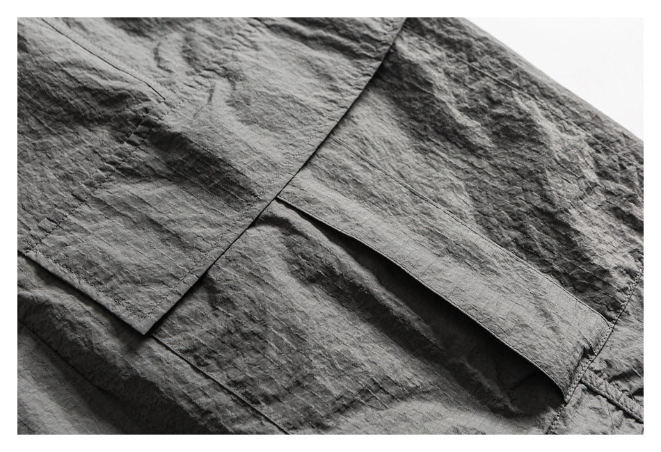 Close-up of charcoal gray garment construction, showing a large pocket edge and stitched seams.