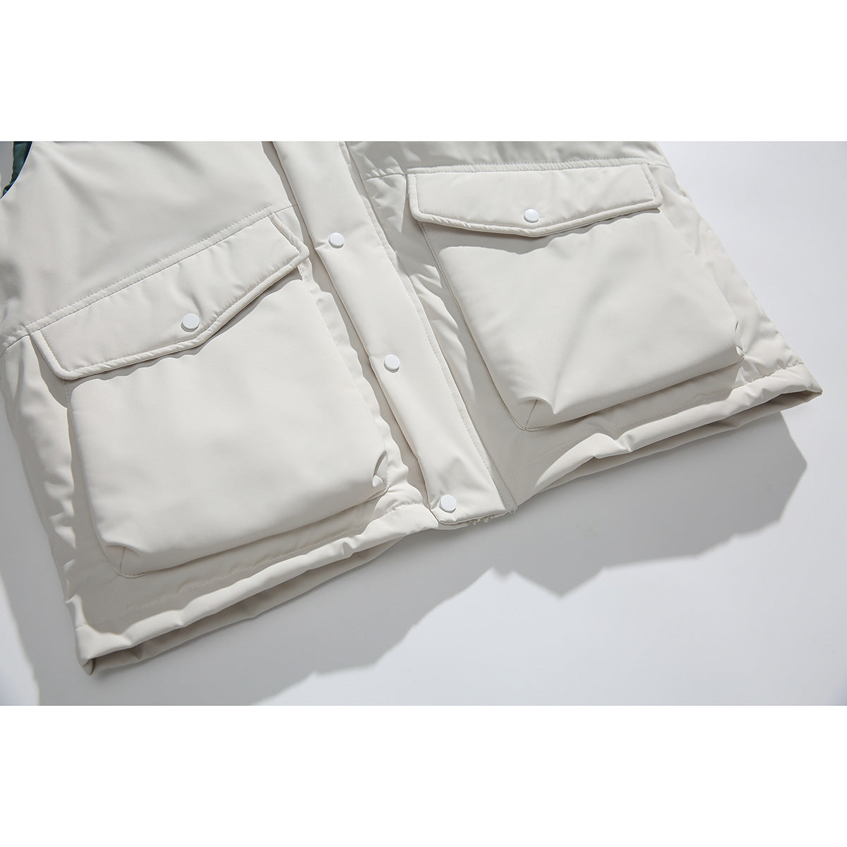 Close-up of two large snap-flap pockets and the buttoned placket on an ivory vest.