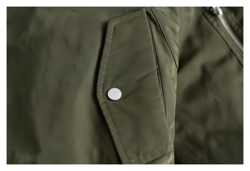 Close-up of an olive jacket flap pocket with a silver snap and zipper edge.