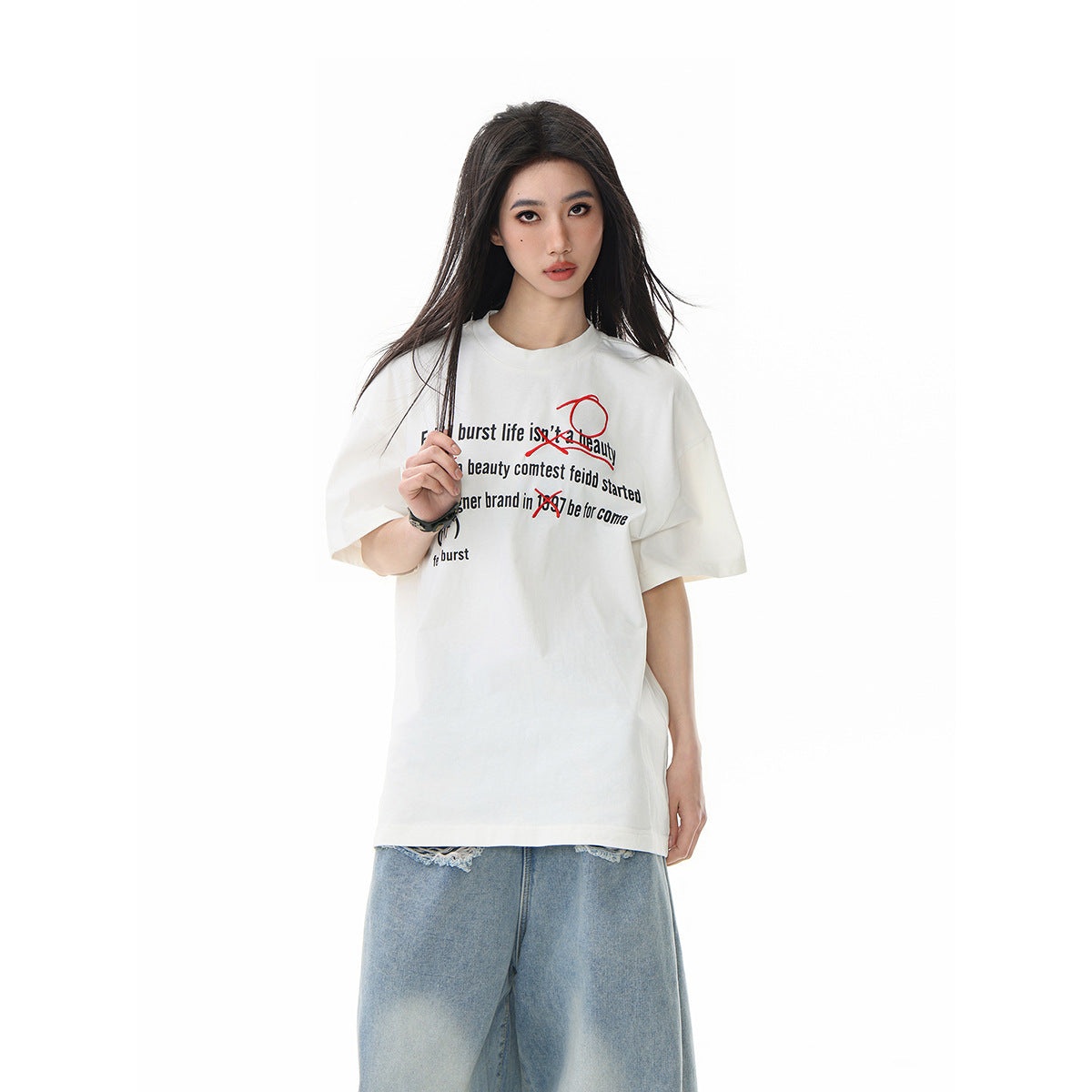 Front view of a model in an off-white oversized graphic T-shirt with black text and red marks, paired with wide light-wash