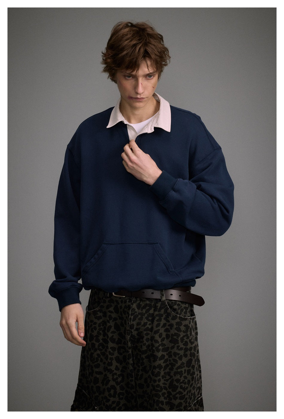 Close view of a model wearing a navy pullover with a pale pink collar and kangaroo pocket.