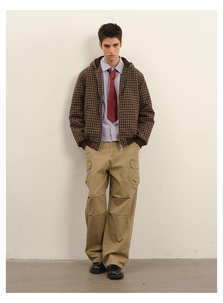 Model leaning on a wall in a brown check hooded zip jacket with lavender shirt, red striped tie and khaki cargo pants