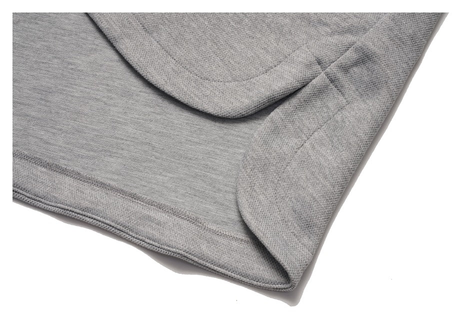 Close-up of a gray sweatshirt's curved hem and side seam.
