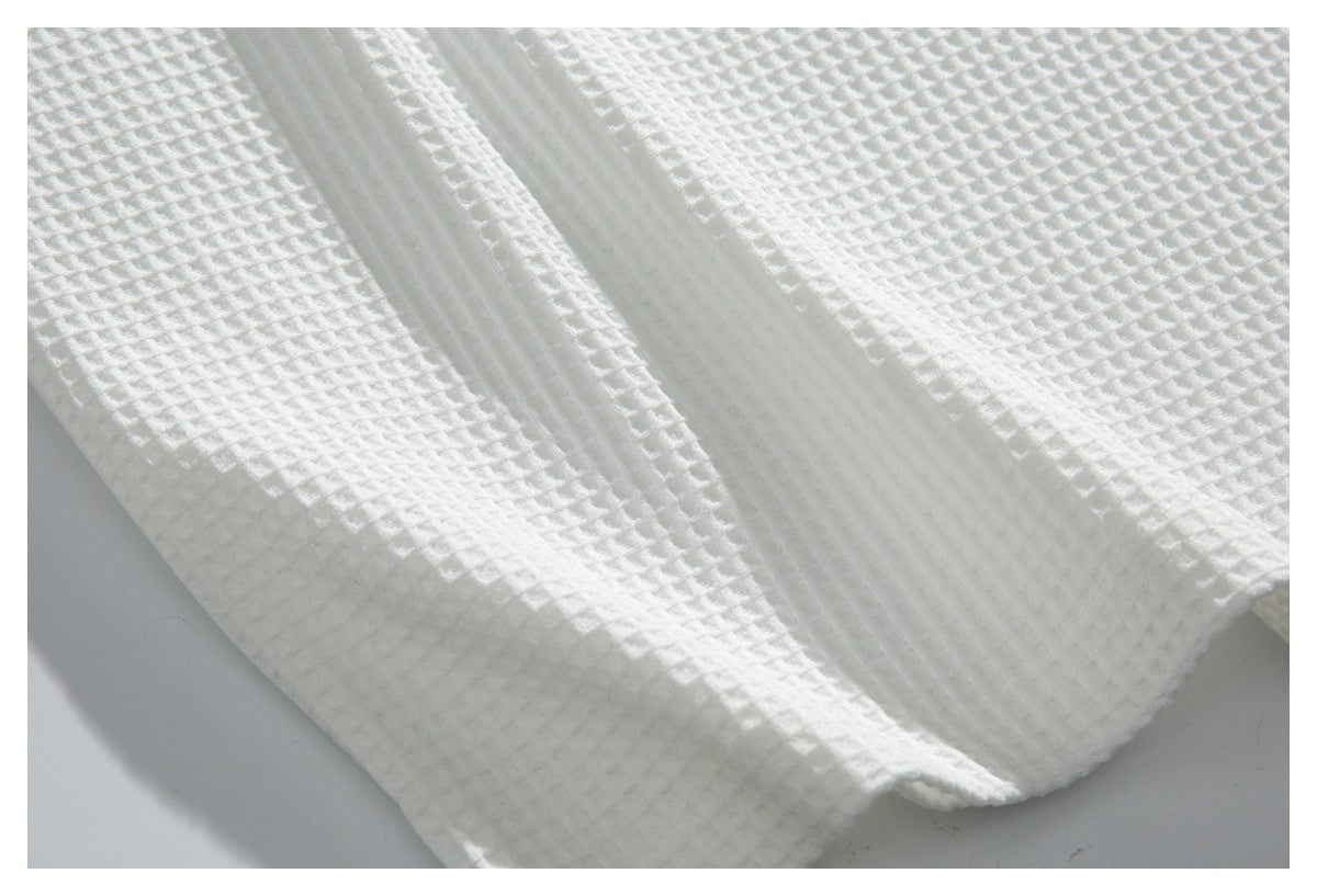 Close-up of white waffle-textured fabric and a folded garment edge.