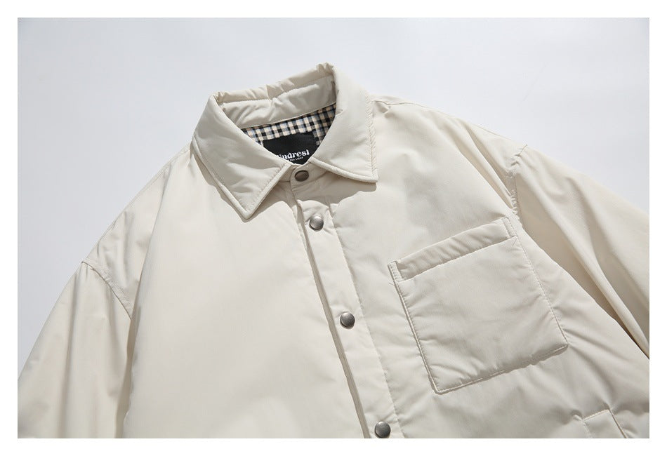 Close-up of the cream jacket's collar, checked inner neckline, snap buttons, and chest patch pocket.