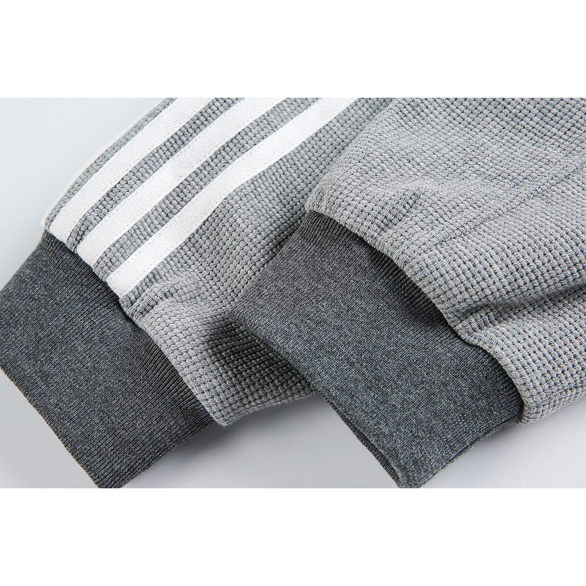 Close-up of the gray jacket's textured sleeve, three white stripes, and dark ribbed cuff.
