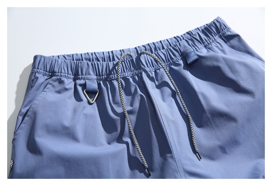Close-up of blue shorts showing an elastic waistband, black-and-white drawcord, and metal loop.
