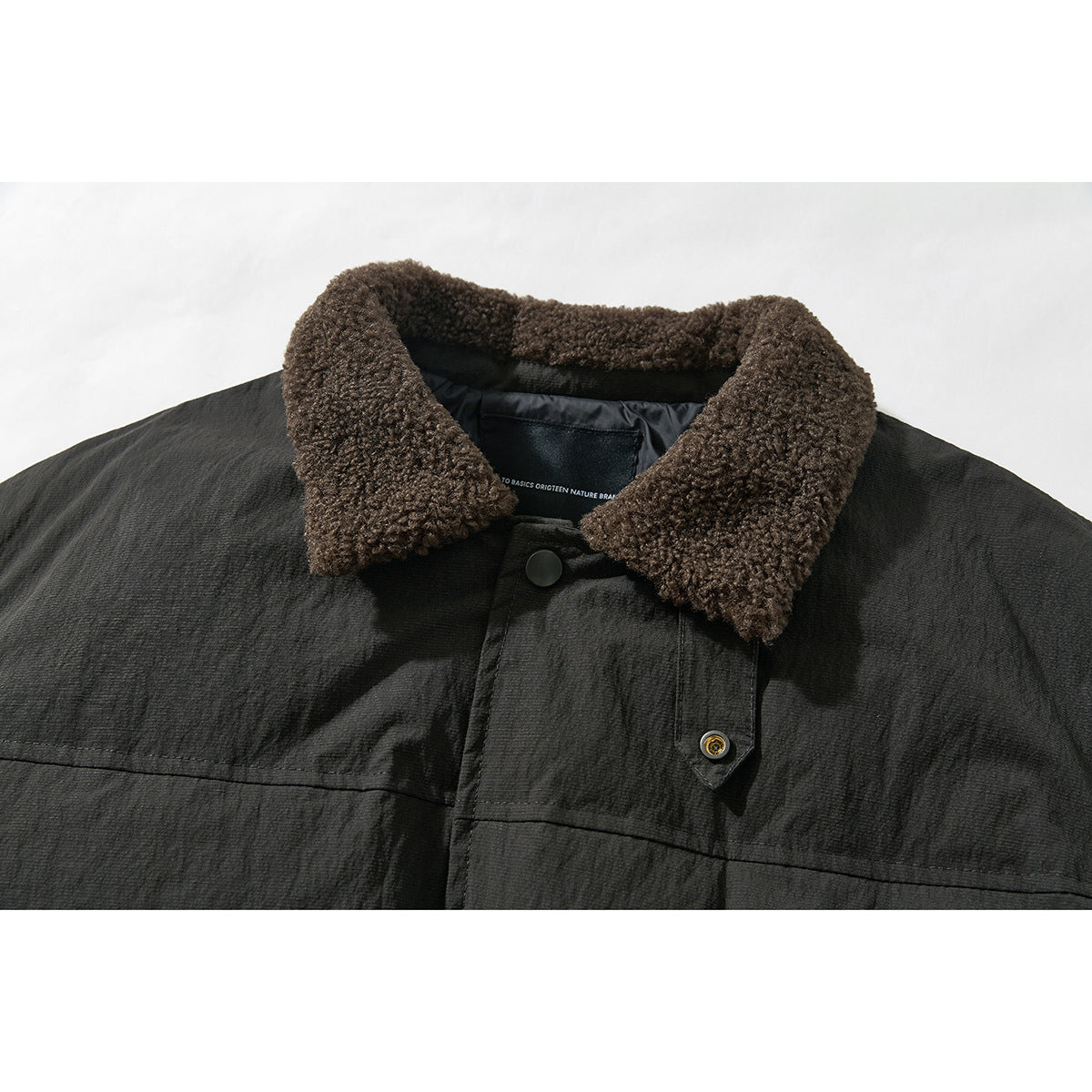 Close-up of a dark jacket with a thick brown textured collar and snap-front placket.