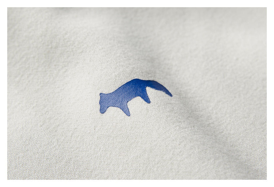 Small blue animal-shaped embroidery on the cream sweatshirt fabric.