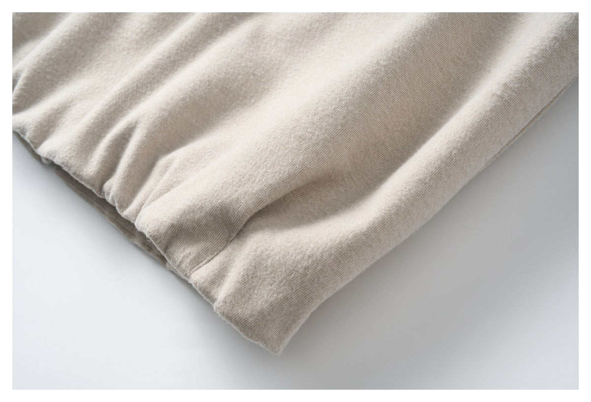 Close-up of a light beige garment showing soft folds and a finished edge.