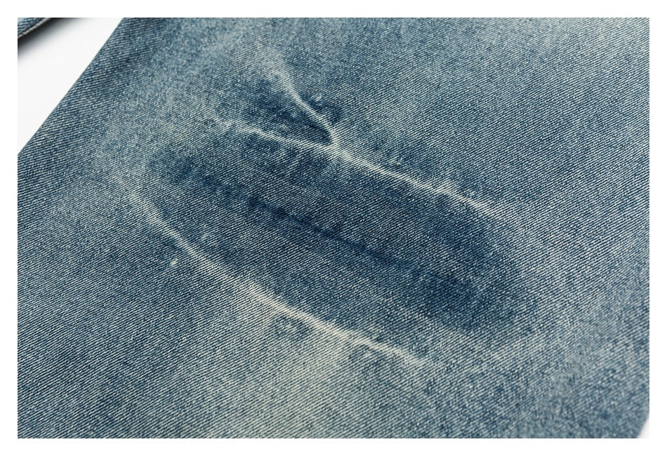 Close-up of blue denim showing a faded oval abrasion mark.