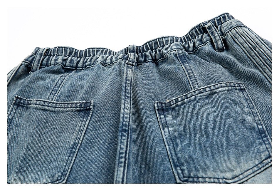 Close-up of blue jeans showing the gathered waistband, belt loops, center seam, and two back pockets.