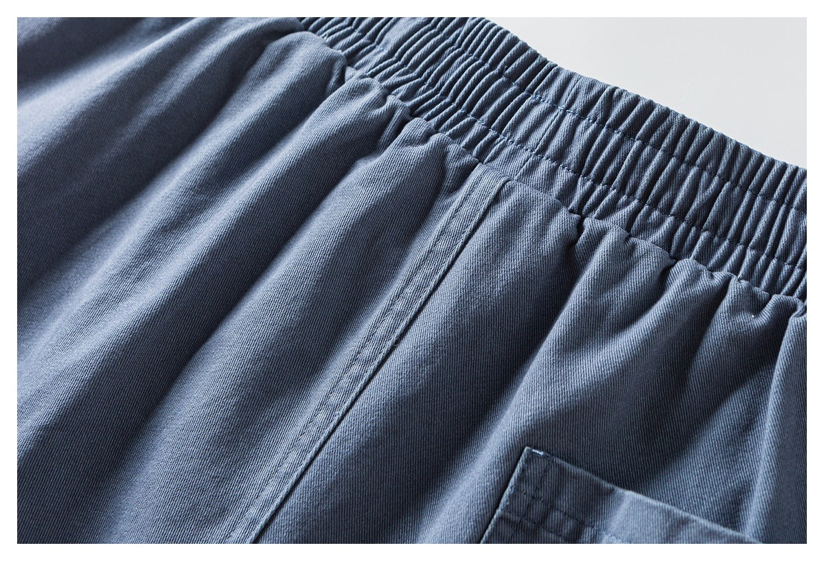 Close-up of the gathered elastic waistband and pocket edge on blue-gray pants.
