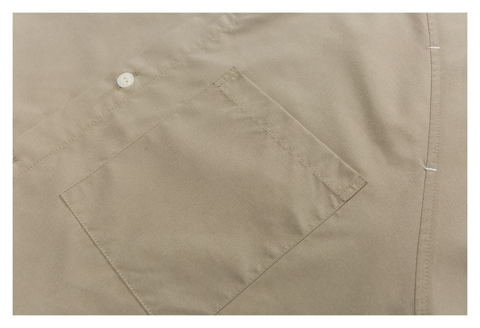 Close-up of a taupe shirt’s angled chest pocket, button, and stitching.