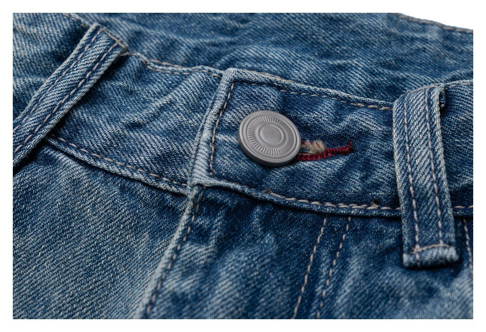Close-up of blue denim waistband with a round metal button, belt loop and red stitched buttonhole.