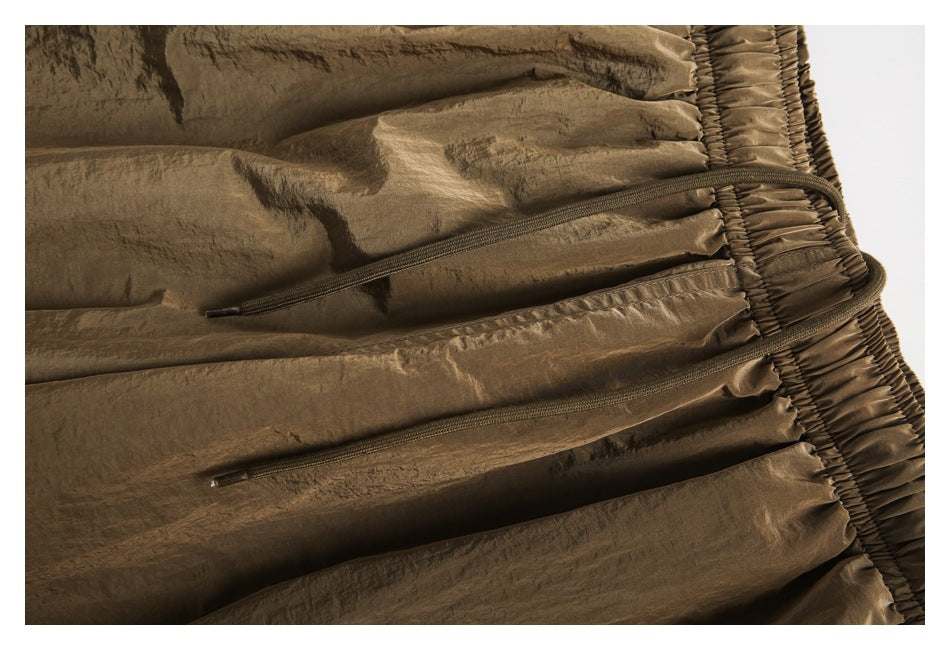 Close-up of brown shorts showing the gathered elastic waistband and two front drawstrings.