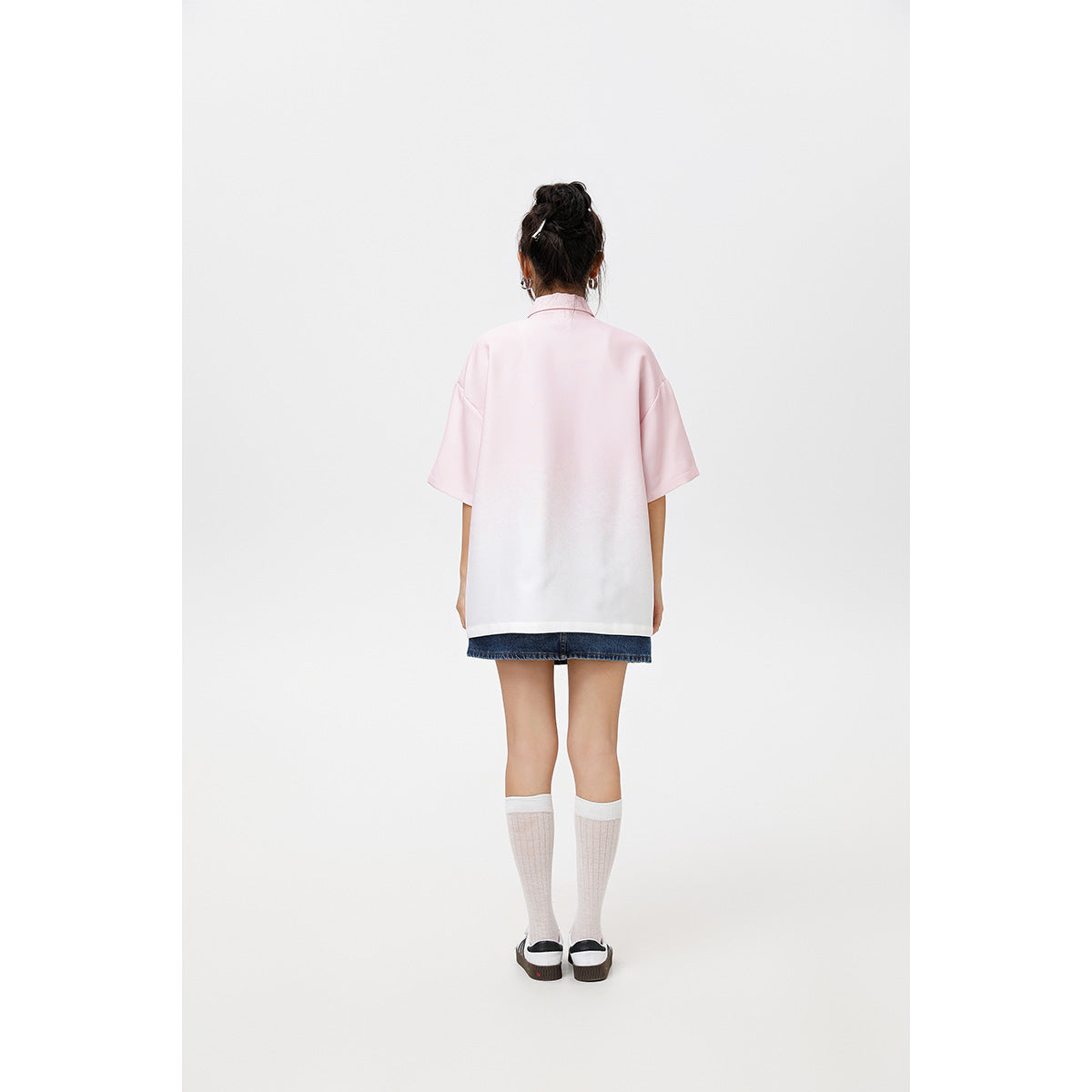 Back view of a model wearing an oversized pink-to-white short-sleeve collared shirt with a plain back.